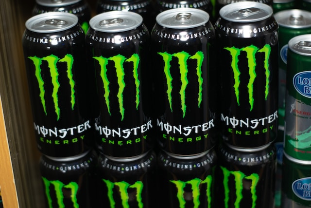 Tins can of Monster Energy drink sits on a table indoors