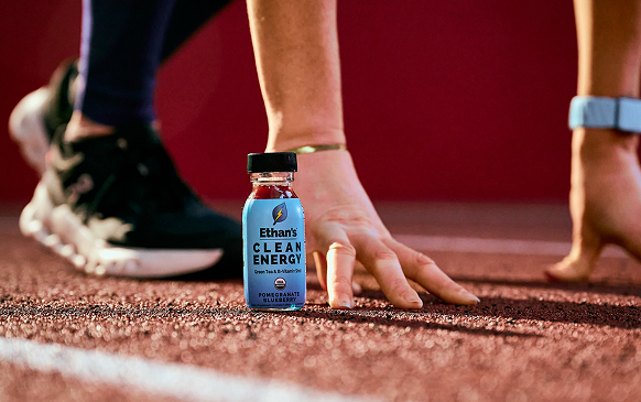 Runner crouched at the starting line next to an Ethan's Clean Energy shot